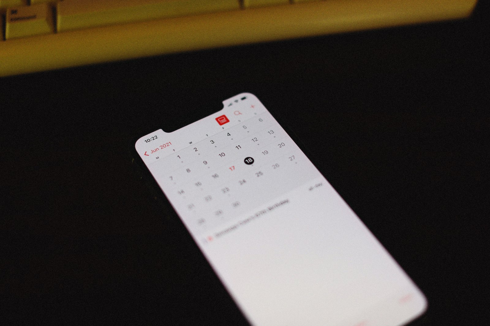 Smartphone showing a generic calendar display on a dark desk.
