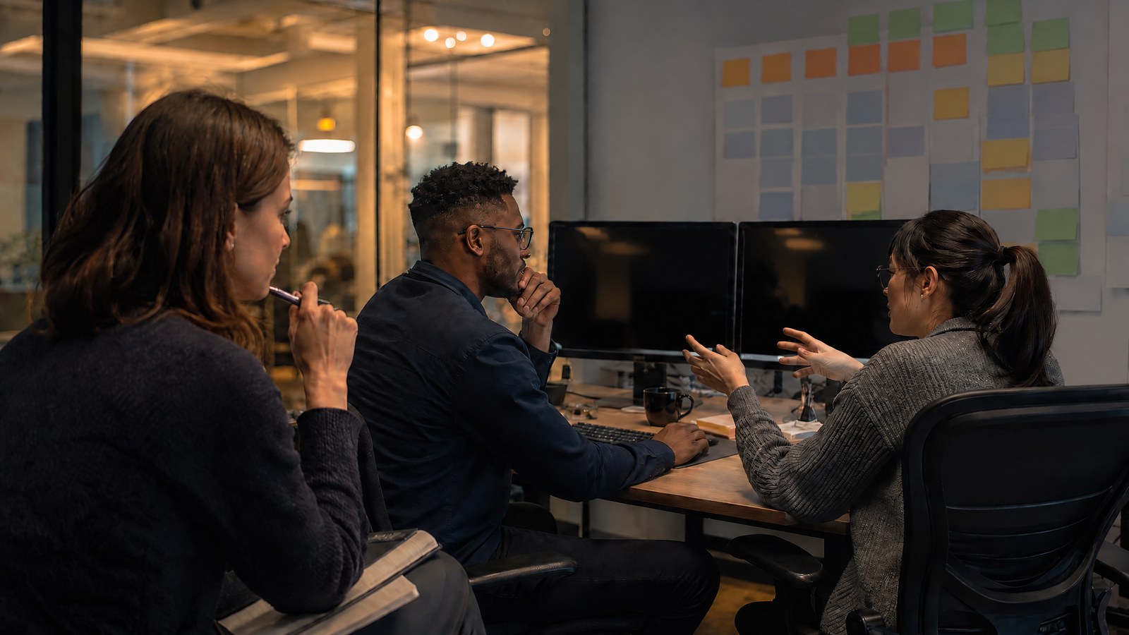 A product researcher watches two software developers use an abstract engineering tool during an in-person usability session, with text-free screens.