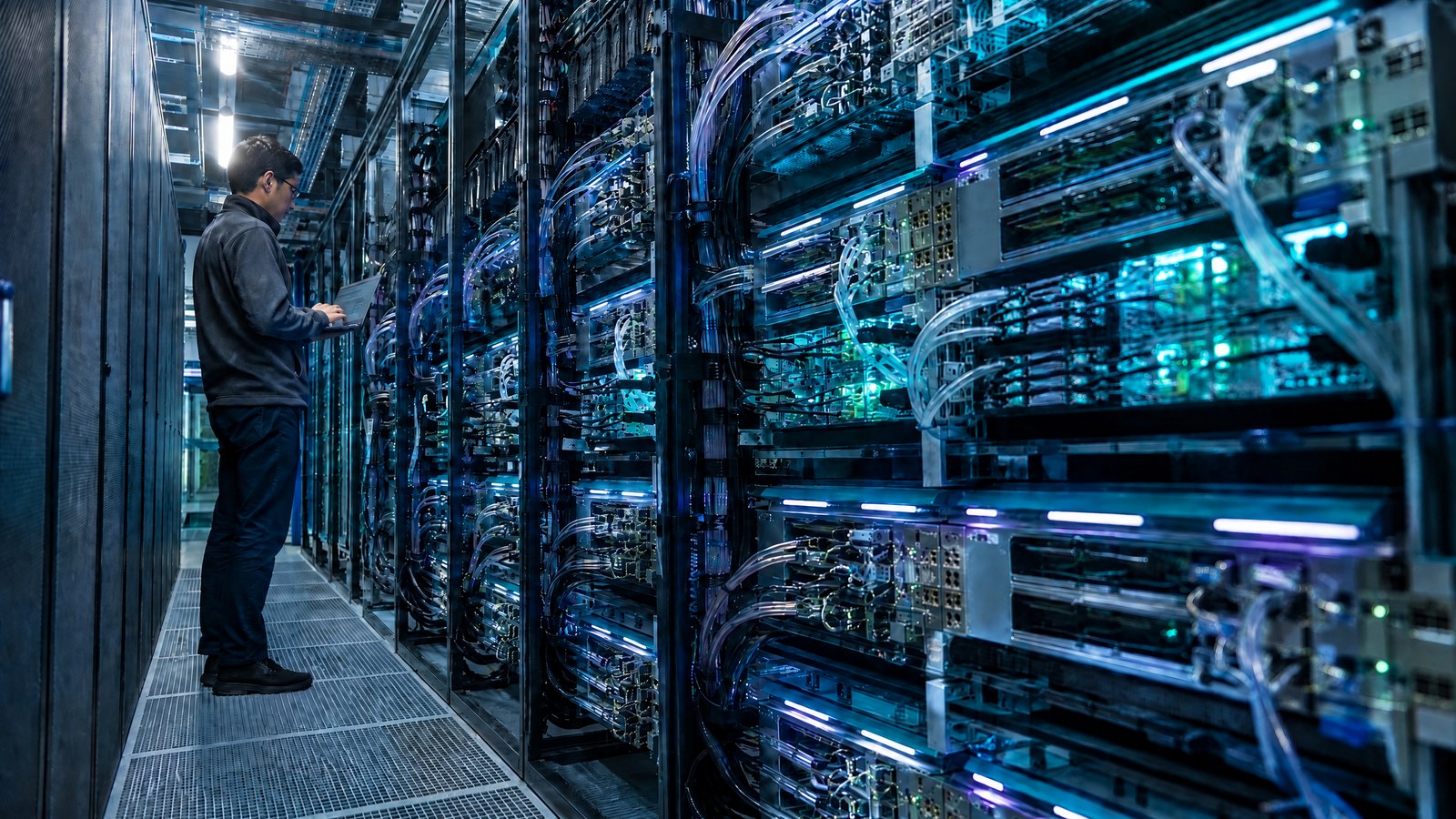 Two data-centre engineers inspect a distributed AI compute cluster with visibly distinct accelerator modules under warm coral light.